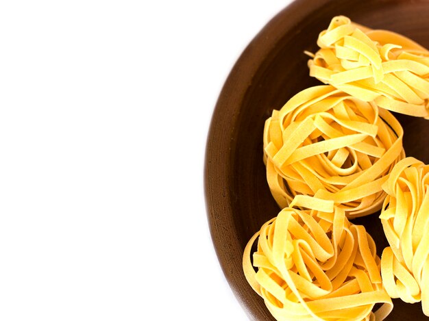 Uncooked tagliatelle on a ceramic plate. Isolated