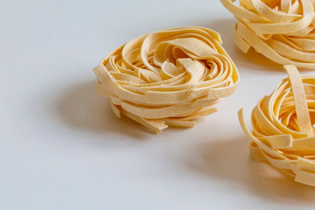 Uncooked tagliatelle on white table