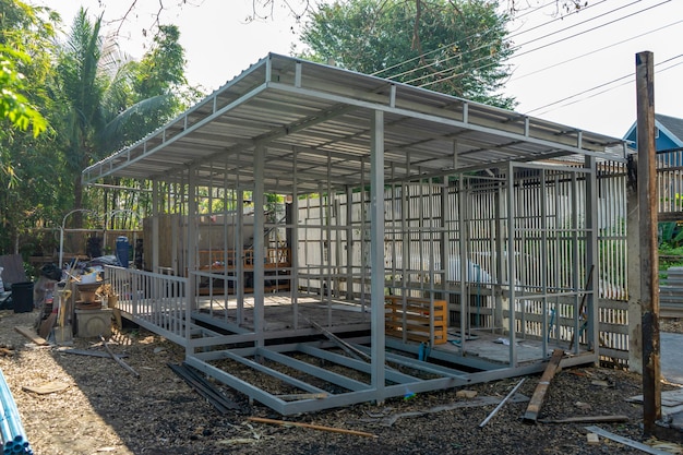 Underconstruction housemaid small temporary home is made from steel pole structure without cement and brick with garden and fence around