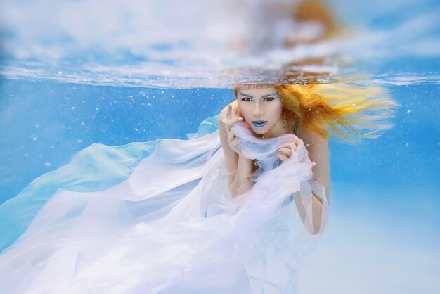 Underwater fashion portrait of beautiful young woman in blue dress