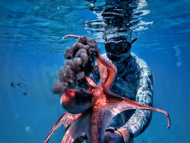 Photo underwater fight between a diver and an octopus