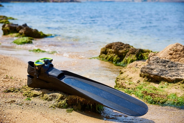 Underwater fins and mask on the beach in sunlight.