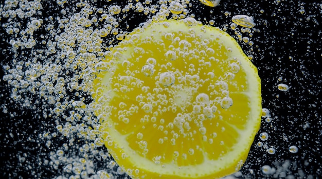 Фото Под водой свежевыжатый подслащенный лимонад, который нарезают сырые лимоны, падающий в газированную воду на темно-синем или черном фоне. крупным планом лимонад или лимонный коктейль highball, холодный освежающий напиток