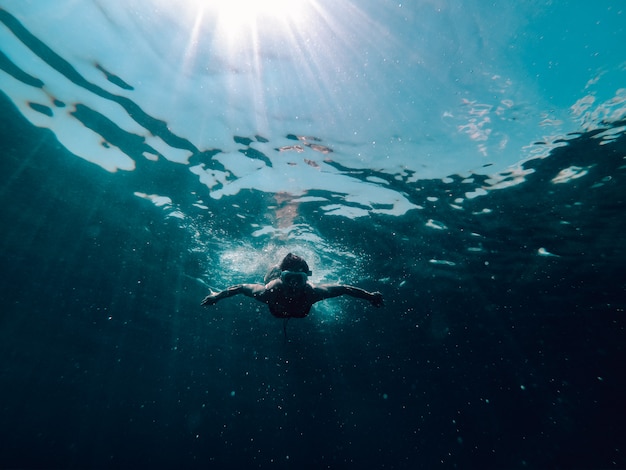 Подводная фотография женщины, плавающей в море