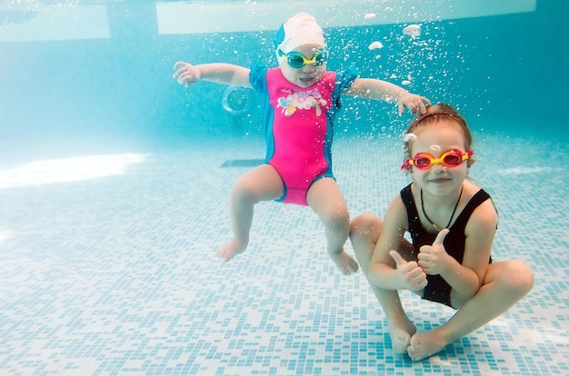 Underwater photo of young friends in swimming pool.