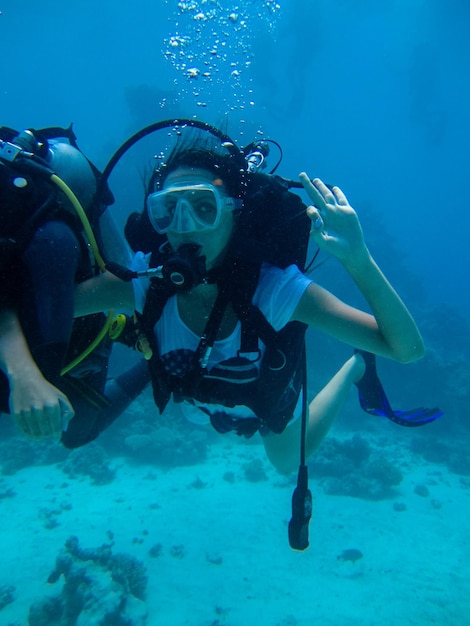 Underwater shoot of a woman diving with scuba and showing ok signal