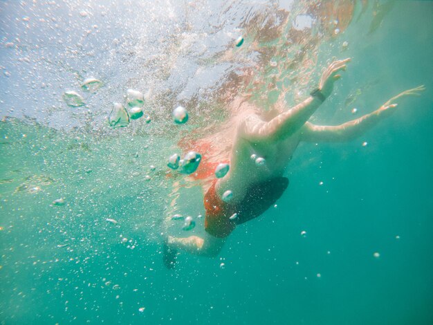 Underwater view man swimming with inflatable pillow