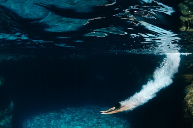 Underwater view of a young boy jumping into the sea