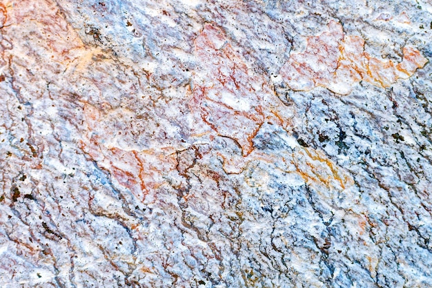 Photo uneven stone texture background, closeup. natural colorful hard rock cracked surface.