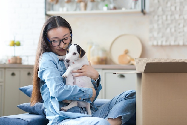 幸せで感動したアジアの若い女性が小さな犬を贈り物として受け取った、予期せぬ楽しい贈り物