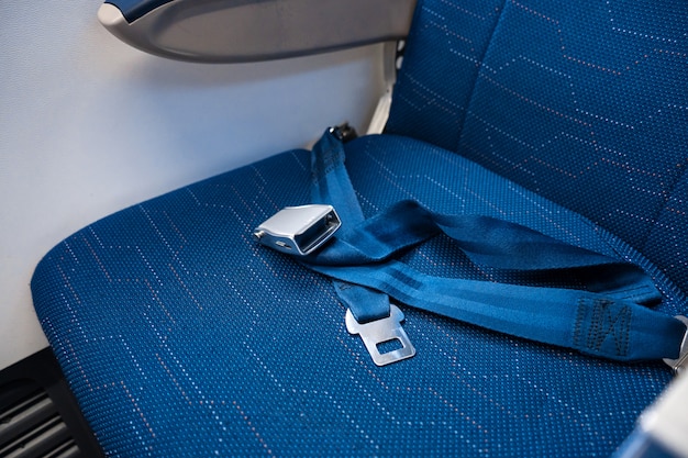 Una cintura di sicurezza sganciata su un sedile vuoto in un aeroplano. sicurezza in volo