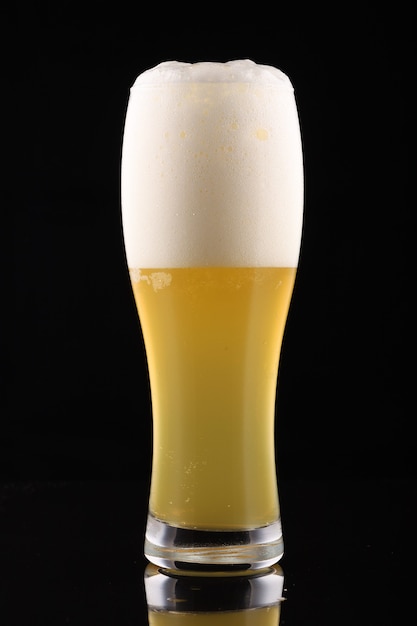 Unfiltered light beer in a glass on black surface