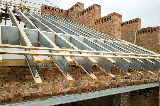 Unfinished brick apartment building with wooden roof structure under construction.