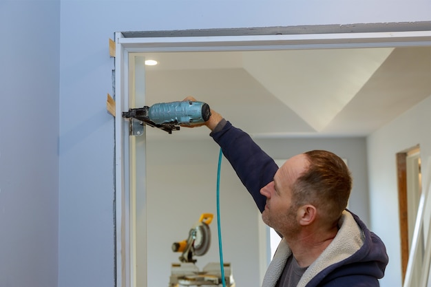 Unfinished house installation a new wooden interior doors in the using air gun nail in the nailing on finishing work