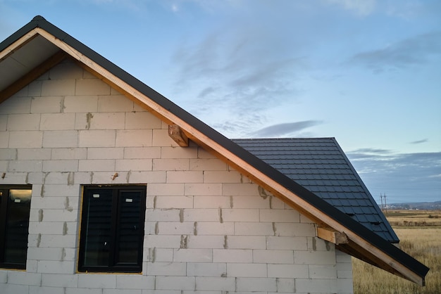 Unfinished house with aerated lightweight concrete walls and wooden roof frame covered with metallic tiles under construction