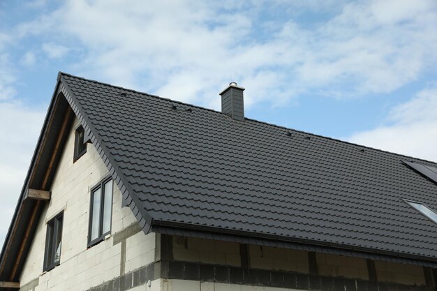 Unfinished house with grey roof against cloudy sky low angle view