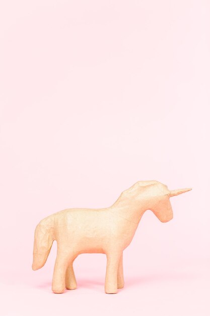 unfinished paper mache figurine of unicorn on a pink background.