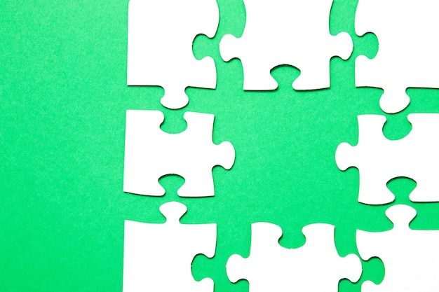 Puzzle incompiuto di cartone bianco su sfondo verde e una parte non adatta di un altro puzzle, manca un pezzo, copia spazio, cerca una parte adatta