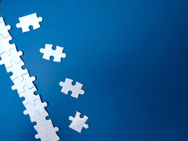 Unfinished white jigsaw puzzle pieces on blue background