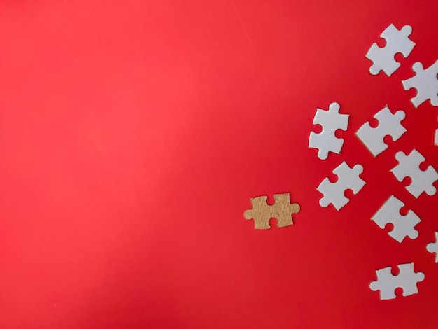 Unfinished white jigsaw puzzle pieces on red background