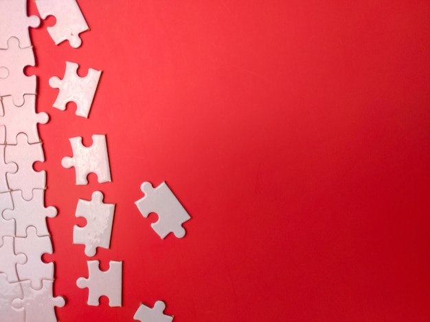 Unfinished white jigsaw puzzle pieces on red background