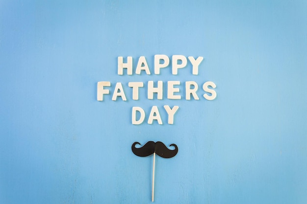 Unfinished wood lettrs sign Happy Father's Day on a painted wood background.