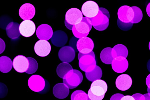 Unfocused abstract purple bokeh on black background. defocused and blurred many round light.