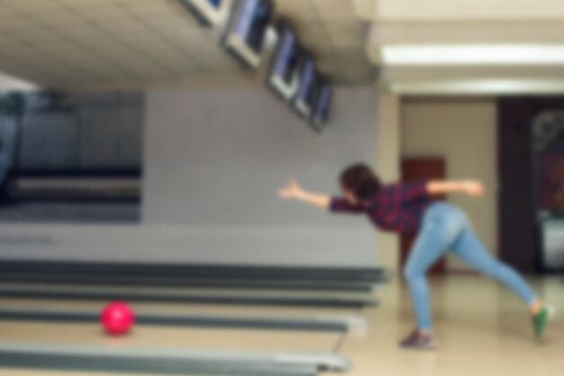 Unfocused photo for background beautiful girl plays bowling in bowling club