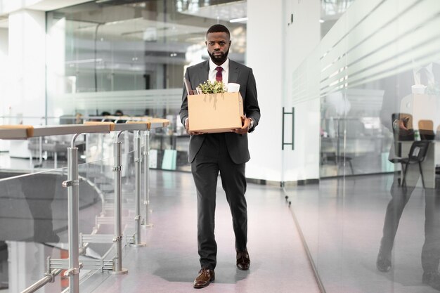 Unhappy african american young man employee with working stuff