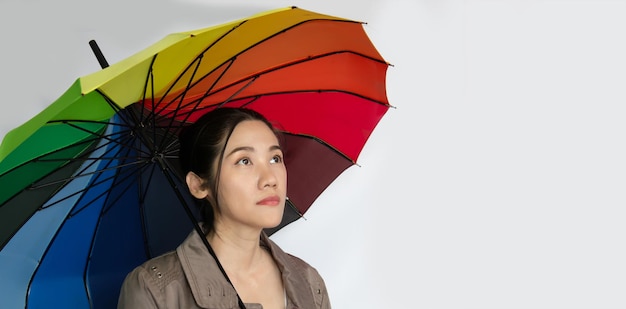 Unhappy Asian beautiful woman hold colored umbrella with lonely and look above on rainy day