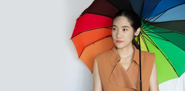 Unhappy Asian beautiful woman hold colored umbrella with lonely and thinking something on a rainy day