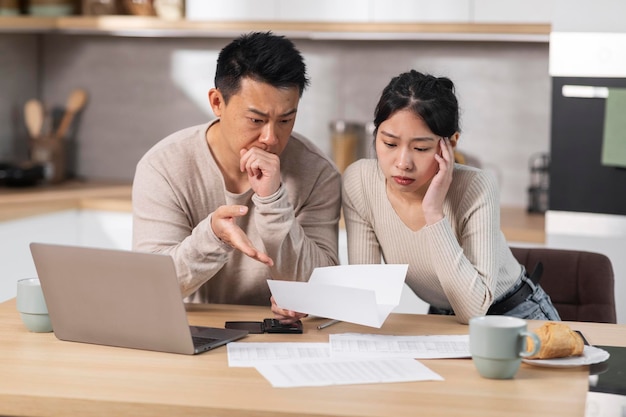 Unhappy asian husband and wife reading letter kitchen interior