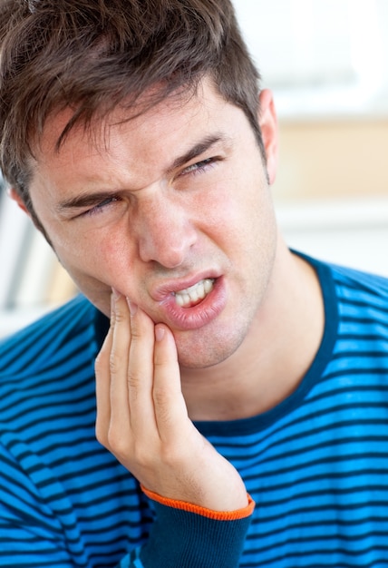 Foto uomo caucasico infelice che ha un mal di denti nel soggiorno