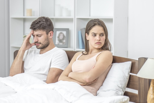 Photo the unhappy couple sit in the bed