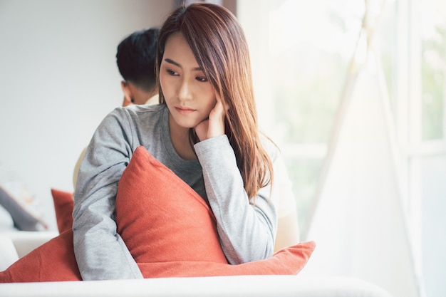 Unhappy Couple sitting behind each other on the couch and avoid talking or looking at each other