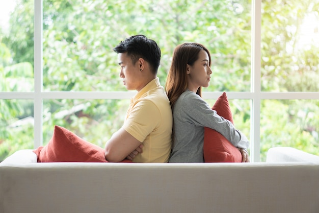 Unhappy Couple sitting behind each other on the couch and avoid talking 