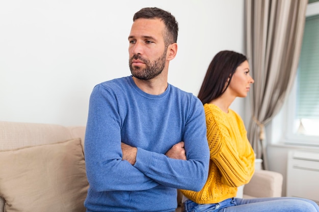 Photo unhappy couple not talking after an argument at home unhappy couple not speaking after having argument young couple in fight with arms crossed sitting on couch after quarrel at home