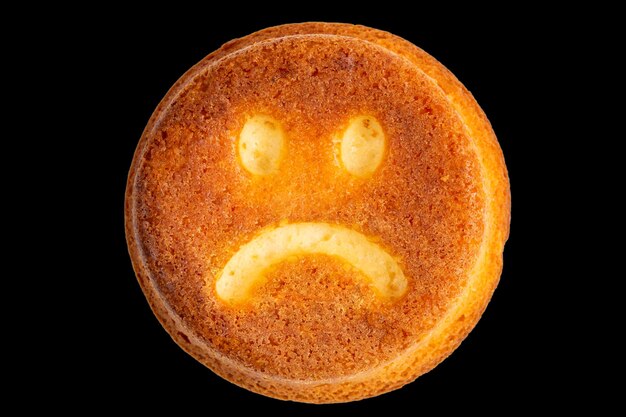 Unhappy face biscuit cookie isolated on black in flat lay perspective