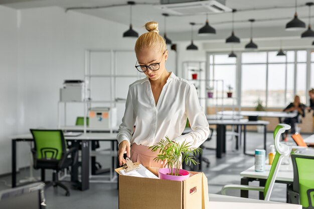 Unhappy female employee packing things at work