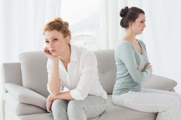 Unhappy friends not talking after argument on the couch