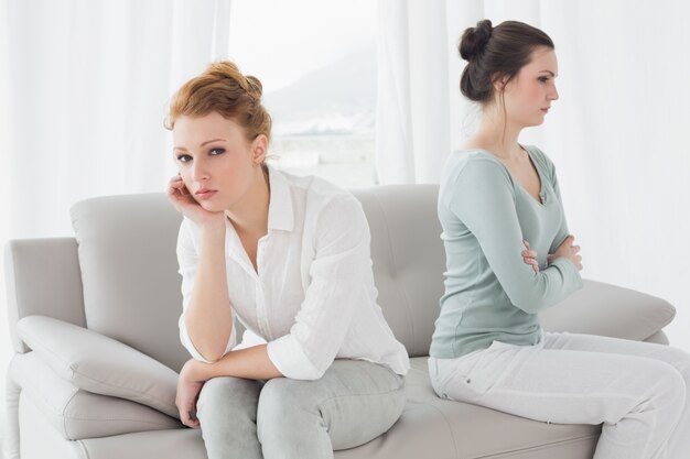 Unhappy friends not talking after argument on the couch