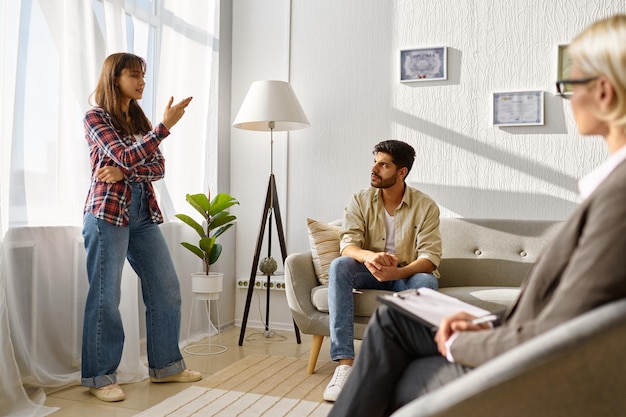 Unhappy frustrated couple arguing discussing relationship problems at psychologists office