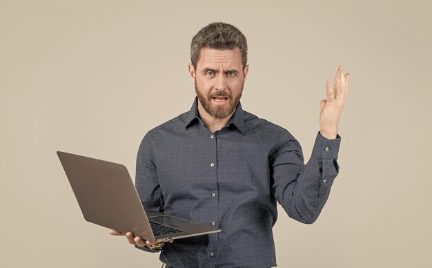 Unhappy handsome mature man businessman with beard working online on laptop boss