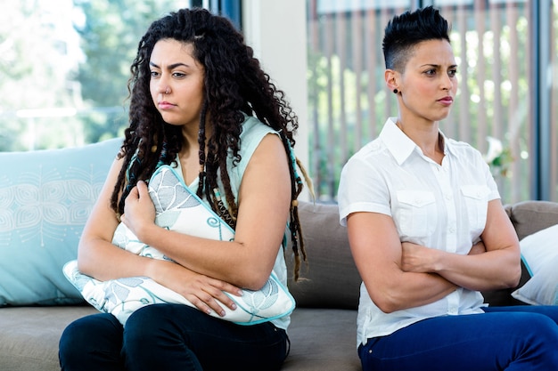 Unhappy lesbian couple sitting on sofa in living room