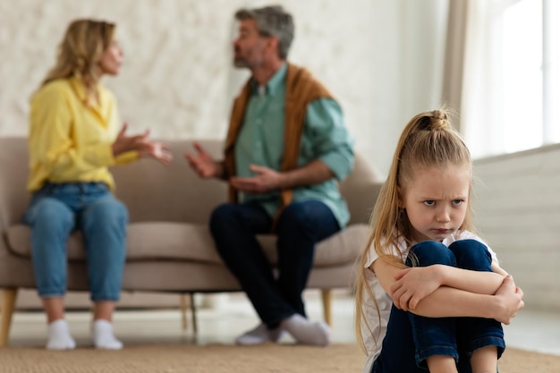 Unhappy little daughter listening to quarrel between parents at home