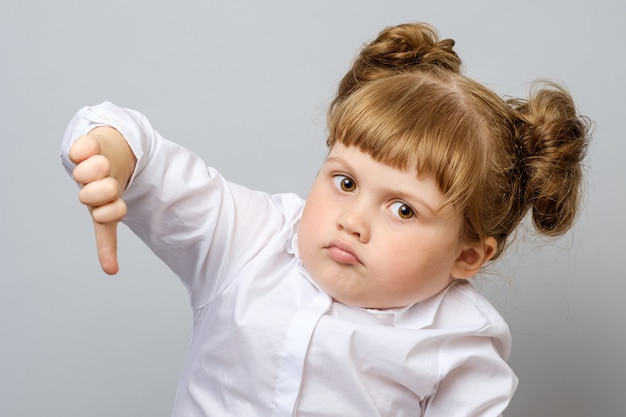 Unhappy little girl showing thumb down