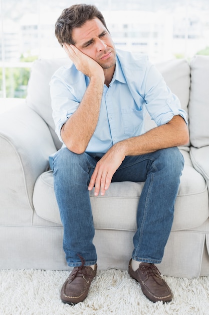 Unhappy man sitting on the couch looking away