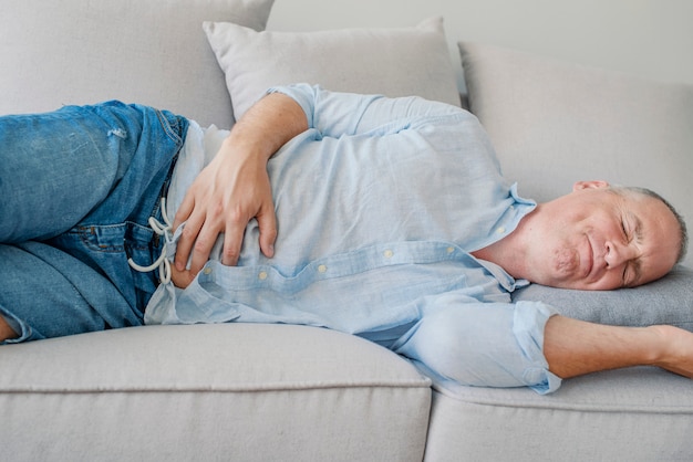 Foto uomo infelice che soffre di mal di stomaco a casa