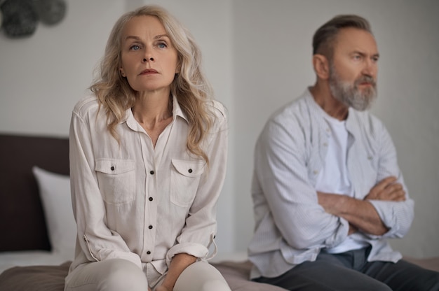 Unhappy mature couple sitting apart in silence