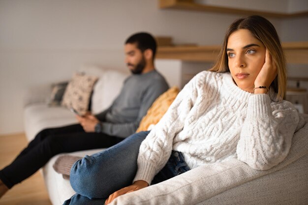 Photo unhappy millennial arabic husband plays in game on smartphone ignores european wife in room interior